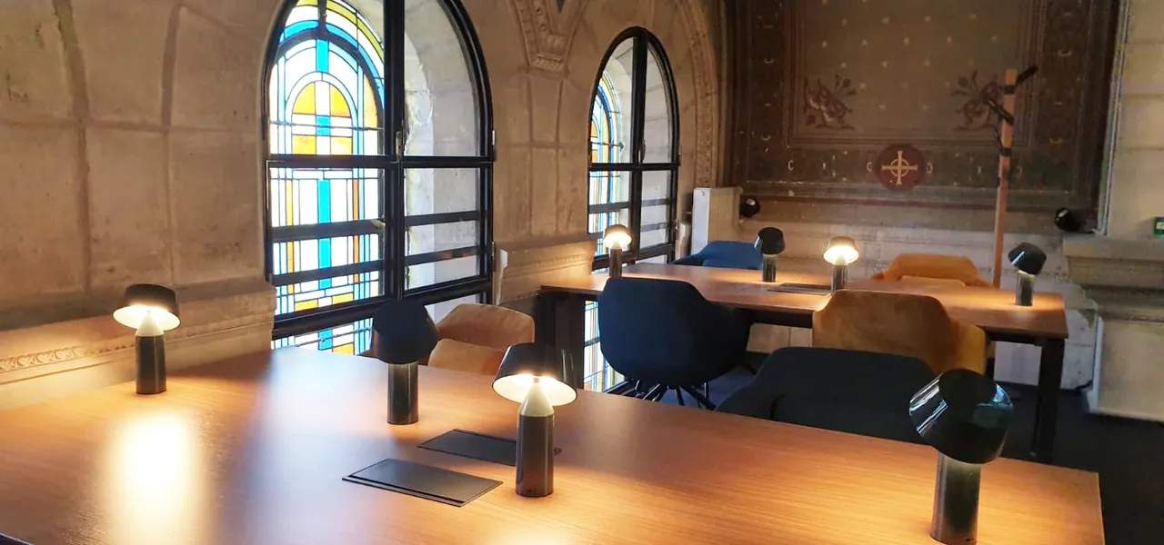 Bureaux alignés devant de grands vitraux en arc