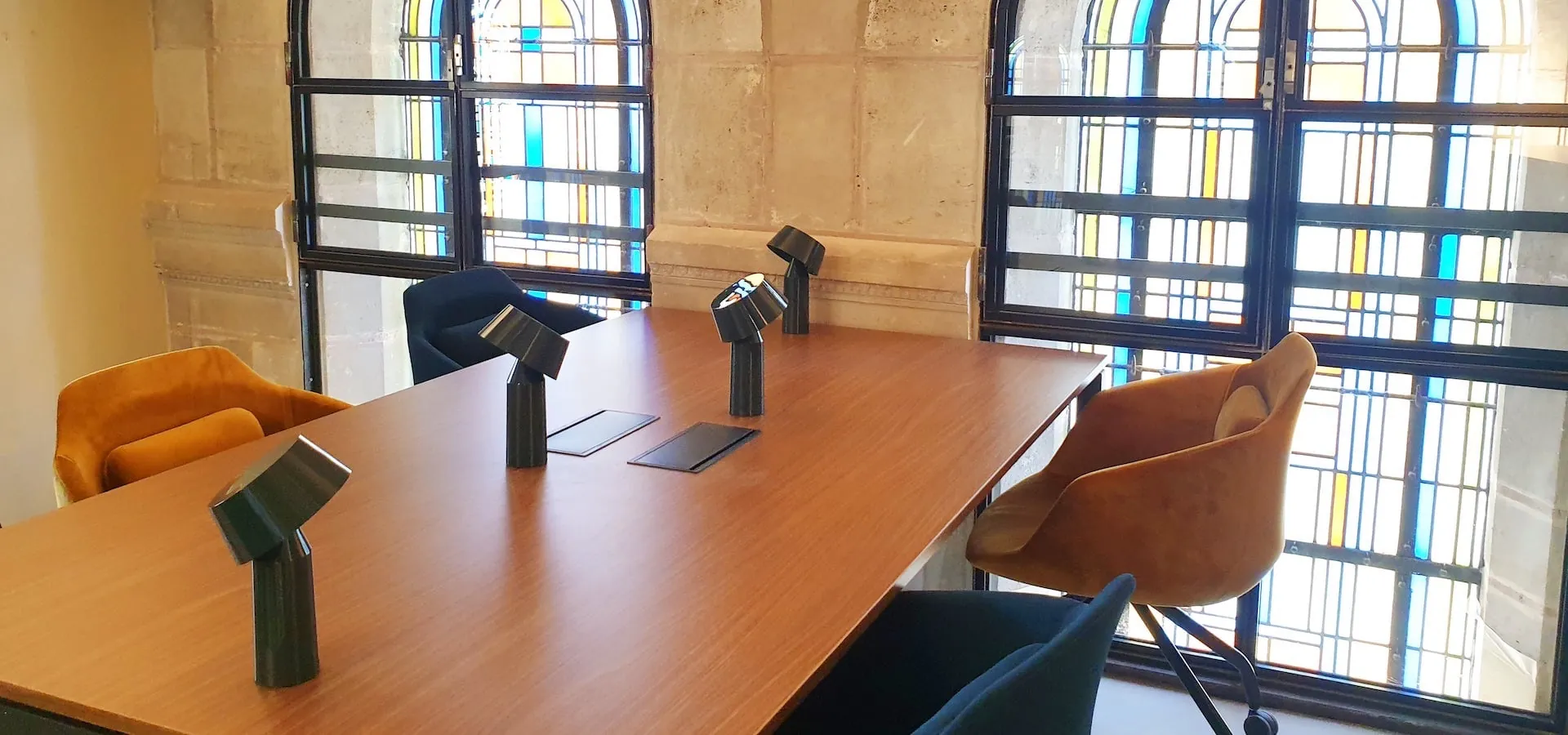 Bureau sous un grand vitrail, avec table de travail et lampes