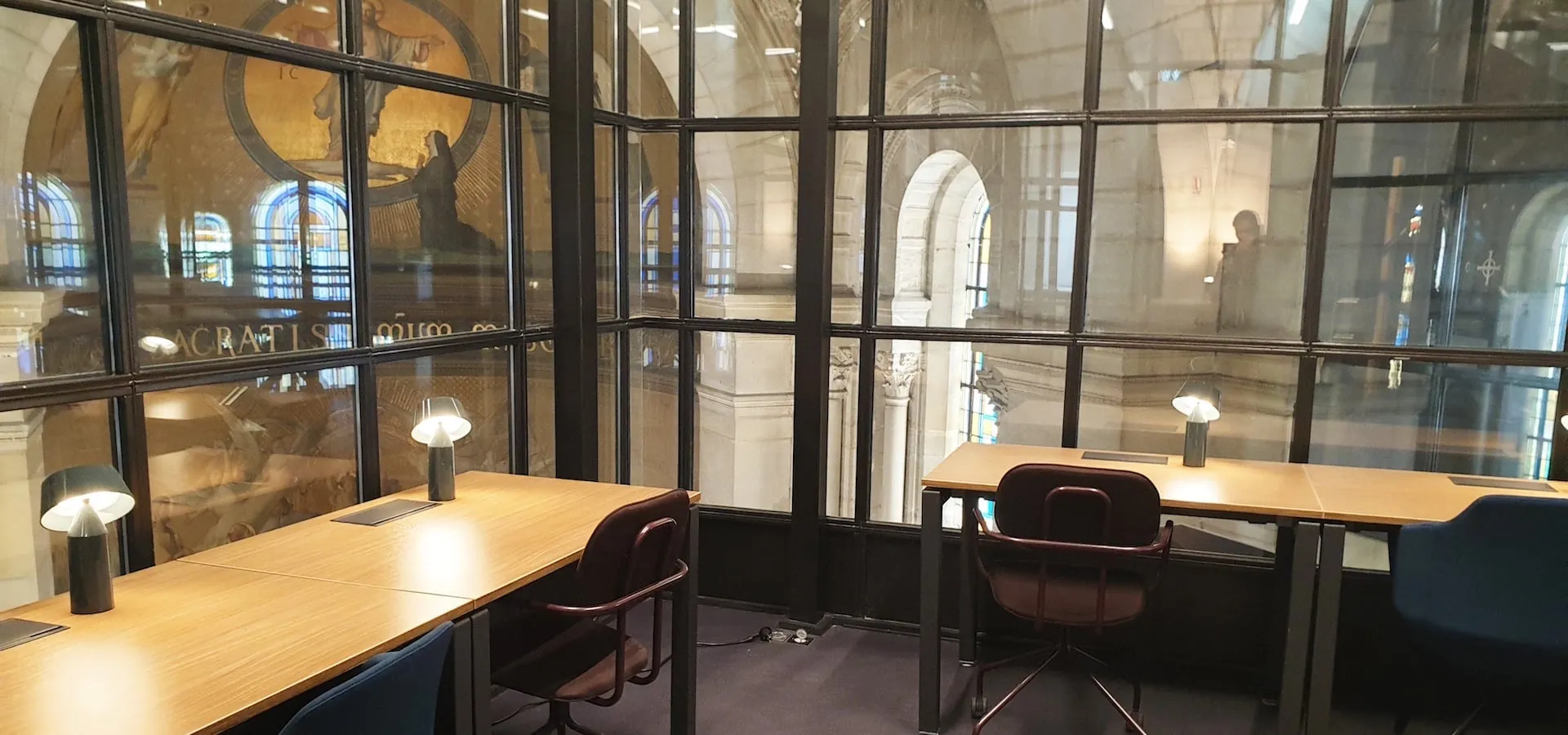 Bureaux dans une cage vitrée qui reflète les fresques de la chapelle